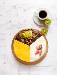 Homemade sweet cake with fruits, chocolate, apple, kiwi, strawberry, orange on white background with cup of coffee americano. Organic dessert sugarless, no fat. Healthy eating.