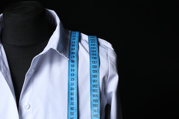Mannequin with shirt and measuring tape on dark background