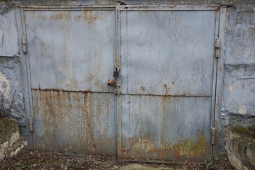 gray iron rusty gate on the facade of an old street garage