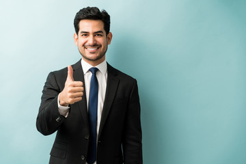 Portrait Of Businessman Showing Hand Sign In Studio