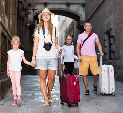Young family of tourists walking with suitcases