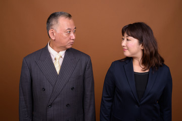 Mature Asian businessman and mature Asian businesswoman looking at each other