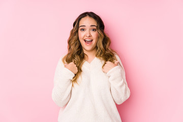 Fototapeta premium Young curvy woman posing in a pink background isolated surprised pointing with finger, smiling broadly.
