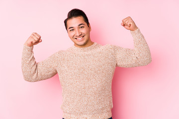Young curvy man posing in a pink background isolated showing strength gesture with arms, symbol of feminine power