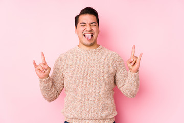 Young curvy man posing in a pink background isolated showing rock gesture with fingers
