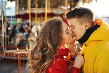 closeup portrait young romantic enamored couple hugging and kissing on french carousel background. © vitaliymateha