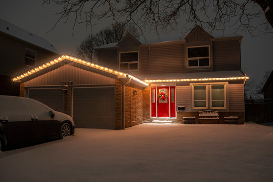 Nighttime Shot of a Detached Suburban House With a Red Door All Lit Up with Christmas Lights