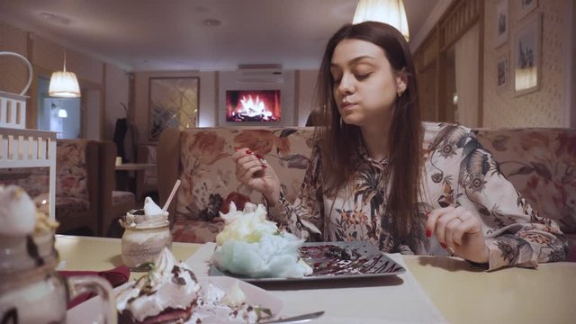 Long-haired girl eating cheesecake in a cafe. rest in a good institution