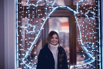 girl christmas lights evening decorated city, a young model on the background of urban decorations and garlands, night city lights