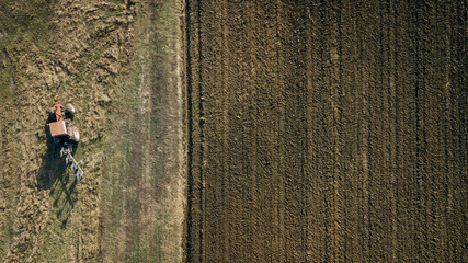 Panoramic aerial view of agricultural cultivated field with tractor performing fall tillage