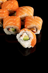 delicious Philadelphia sushi with avocado, creamy cheese, salmon and masago caviar isolated on black