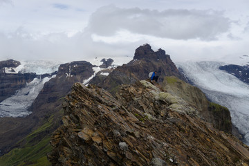  A photographer on the top of the mountain in Iceland. View to a melting glacier tongue of the biggest glacier in Europe called Vatnajökull. 