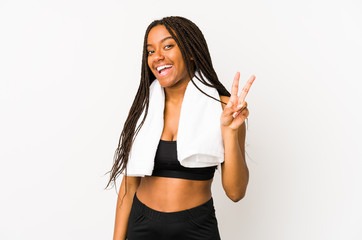 Young african american sport woman isolated joyful and carefree showing a peace symbol with fingers.