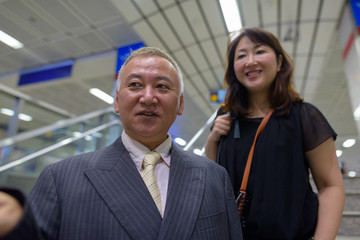 Mature Asian businessman and mature Asian woman at the subway station together