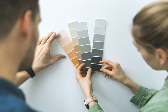 young couple choosing paint color from samples for new home interior design