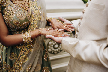 Front view of indian groom's and bride hands in traditional wedding outfits