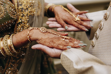 Indian bride's hands coloured with henna on the groom's hands, traditional wedding accessories