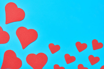 Scattered little and big red paper hearts on blue background. Concept of Valentines Day. Space for text. Top view