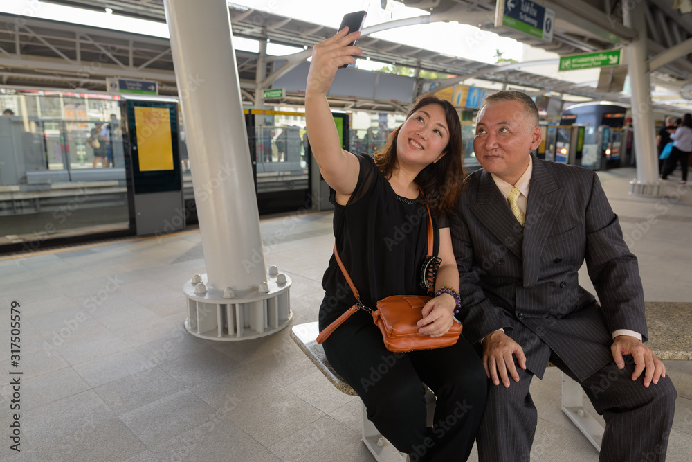 Wall mural Mature Asian businessman and mature Asian woman exploring the city together