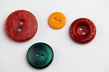 Four multi-colored buttons for clothes on the table.