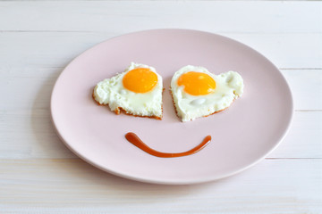 Two fried eggs on pink plate for healthy breakfast on wooden table. top view
