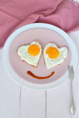 Two fried eggs on pink plate for healthy breakfast on wooden table. top view