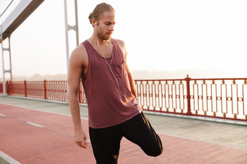 Attractive young fit sportsman working out on a bridge