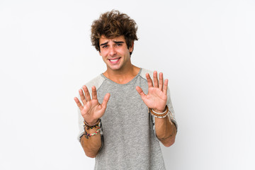 Young caucasian man against a white background isolated rejecting someone showing a gesture of...