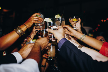 Hands with drinks on the dark background, wedding celebration, cocktails