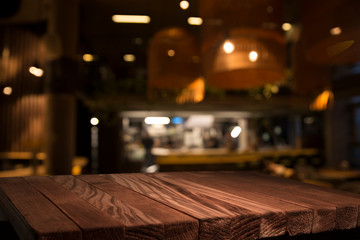 Empty brown wooden table and blur background of abstract of resturant lights people enjoy eating ,can be used for montage or display your products - obrazy, fototapety, plakaty