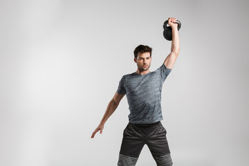 Image of young strong man doing exercise with weight while working out