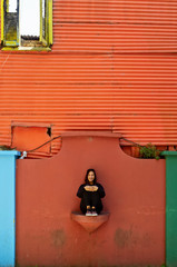 A tourist woman sitting in front of some colorful walls in Caminito Street, Buenos Aires