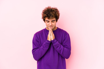 Fototapeta na wymiar Young caucasian man against a pink background isolated holding hands in pray near mouth, feels confident.