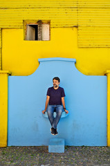 A tourist man sitting in front of some colorful walls in Caminito Street, Buenos Aires