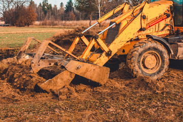 The excavator is digging the ground for the foundation and construction of a new road in the village.