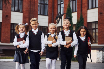 Group of kids in school uniform that is outdoors together near education building