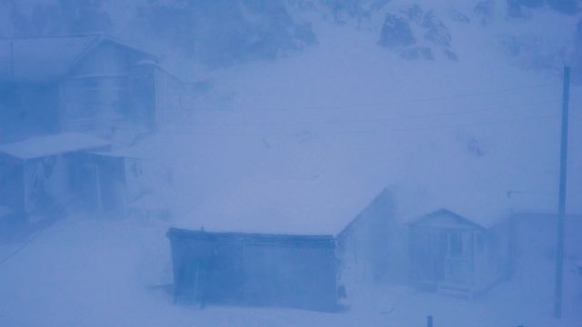 Arctic Storm Battering Wooden Houses With Heavy Winds And Snowfall Gives The Image A Painterly Effect While Giving A Sense Of Cold Harsh Weather And Environment