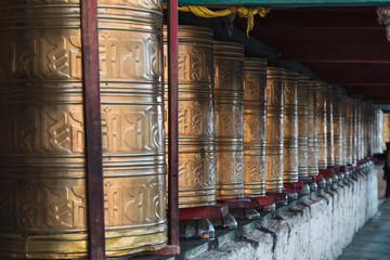 Rows of ancient traditional golden wheels of tibetan temple
