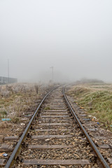 Fototapeta na wymiar Railway in the fog. Train tracks disappear into strange glowing fog