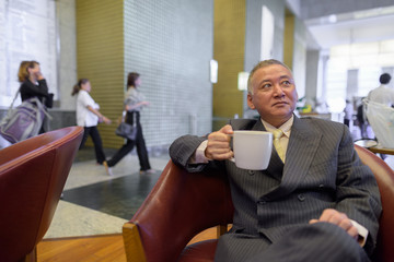 Mature Asian businessman relaxing inside the coffee shop