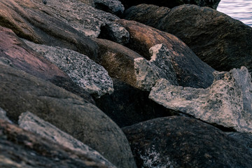 Piles of boulders spread all over the coast; Macro texture of granite and sand