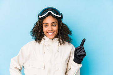 Young african american skier woman isolated smiling and pointing aside, showing something at blank space.