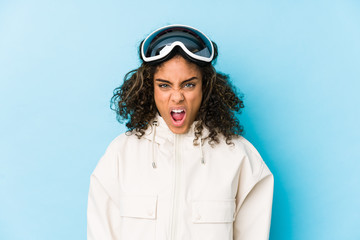 Young african american skier woman isolated screaming very angry and aggressive.
