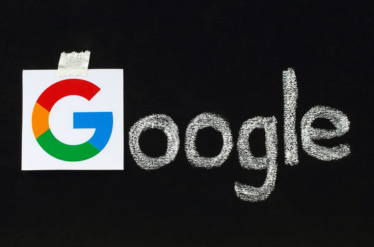 Kiev, Ukraine - September 02, 2015:New Google logotype printed on paper, cut and pasted on blackboard with chalk finish writing.Google is USA multinational corporation.