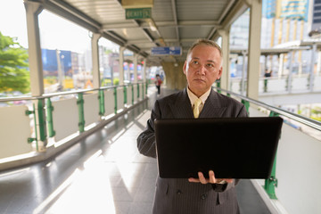 Fototapeta premium Portrait of mature Asian businessman exploring the city