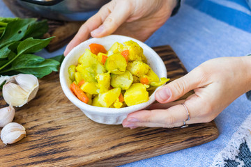 Hands hold vegetable stew. Potato, cabbage, cauliflower, carrot. Vegan food and healthy diet.