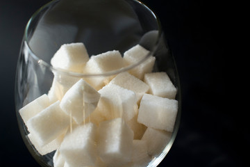 white sugar cubes in a wine glass on black background