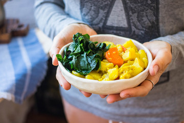 Hands hold vegetable stew. Potato, cabbage, cauliflower, carrot. Vegan food and healthy diet.