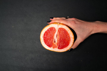 Hands of a young woman holding a red grapefruit