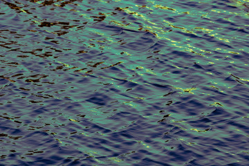 Texture of water with a small ripple and sun rays, with a small turquoise shade